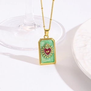 Detail van gouden tarot hanger met rood hart, oogmotief en elegant groen emaille