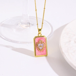 Macro-detail van een gouden tarotkaart ketting met roze emaille hart en oog design