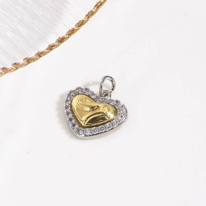 Detail eines Herzanhängers mit goldenen Baby-Fußabdrücken und weißen Zirkonia