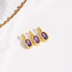 Detailed macro shot of three purple oval zircon pendants with gold metal bases and round loops