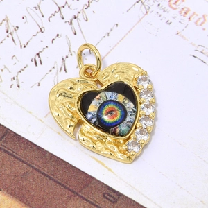 Detail van gouden hart hanger met regenboog oog en zirkonia op vintage papier