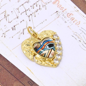 Detailopname van de hartvormige hanger met boze oog, gehamerd goud en zirkoon