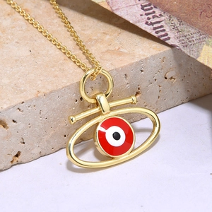 Bohemian gouden evil eye ketting met rode emaille hanger op stenen display