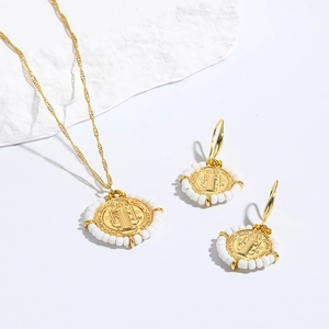 Detalle de un conjunto de joyas de moneda de oro vintage con cuentas blancas y grabado