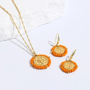 Detalle de conjunto religioso con collar de la Virgen María y pendientes de cuentas naranjas