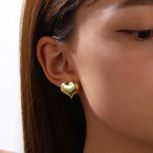 Nahaufnahme minimalistischer hohler herzförmiger Gold-Ohrstecker getragen von Modell