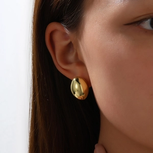 Nahaufnahme eines polierten goldenen ovalen Ohrrings am Model mit Spiegeleffekt