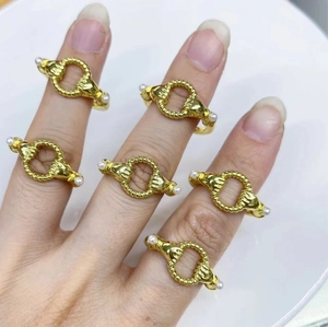 Golden hand-shaped open ring with dual white pearls shown on hand in a white bowl
