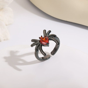Dettaglio anello ragno con pietra a cuore rosso su supporto bianco per Halloween