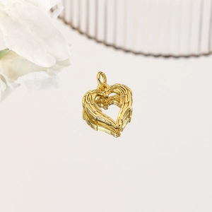 Macro detail of 18k gold plated heart wing pendant with fine engraved texture