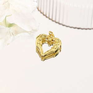 Golden heart wing pendant with feather texture shown at 45-degree angle on mirror