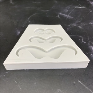 White silicone mustache mold for cake decorating and DIY crafts on dark marble background