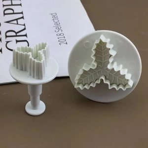 DIY baking set featuring two white holly leaf-shaped cookie and fondant plungers