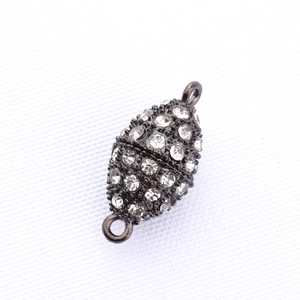 Dettaglio macro della chiusura magnetica a oliva in metallo con strass brillanti