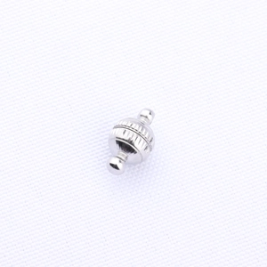 Close-up of silver magnetic clasp for jewelry making with textured wave pattern surface