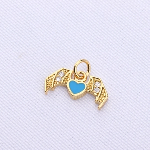 Close-up of golden wing pendant with light blue heart and sparkling zircon accents