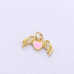 Detail of a gold-plated bat wing pendant with pink enamel heart and sparkling crystals