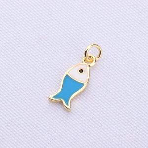 Macro view of a gold plated cartoon fish pendant with blue and white enamel details