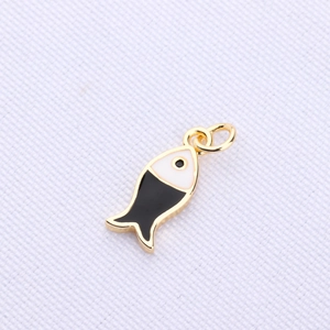 Macro shot of gold-plated fish pendant with black and white enamel finish for DIY jewelry