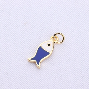 Detailed view of a small fish-shaped jewelry pendant in blue and white enamel with gold trim