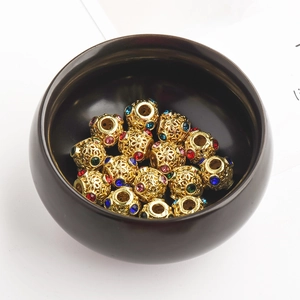 Makroaufnahme vergoldeter Hohlblumenperlen mit bunten Strasssteinen für DIY-Schmuck