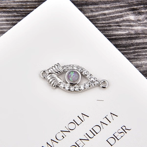 Macro shot of silver evil eye connector with opal stone and zircon for jewelry DIY