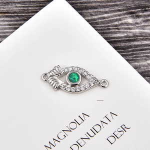 Macro detail of silver evil eye connector charm with green stone and cubic zirconia