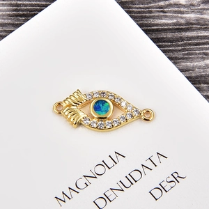 Macro detail of gold evil eye jewelry connector with opal stone and zircon accents