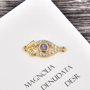 Macro detail of golden evil eye connector with purple opal and sparkling zircons