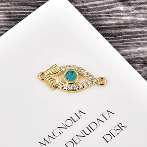 Macro shot of gold-plated evil eye connector with green opal and cubic zirconia inlay