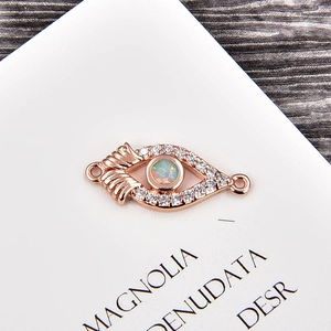 Detailed view of rose gold evil eye connector with opal and zircon for DIY jewelry