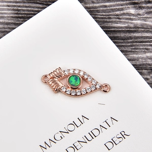 Detail of rose gold evil eye connector with green opal and white cubic zirconia crystals