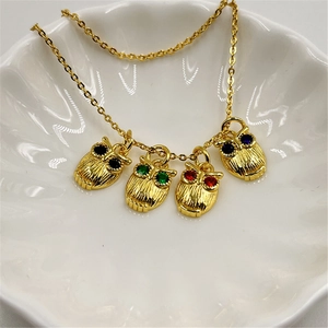Close-up of golden owl pendants with multicolor zircon eyes on an O-shaped chain