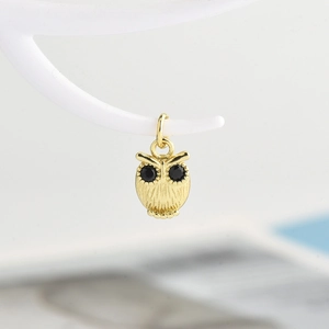 Macro view of a gold owl pendant with intricate textures and black gemstone eyes