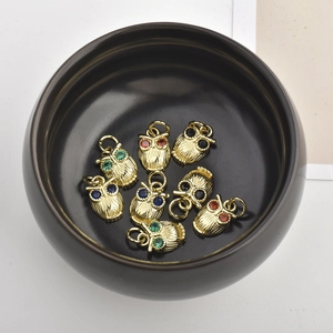 Close-up of brass owl pendants with colored zircon eyes and detailed feather textures