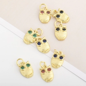Macro shot of owl jewelry pendants with colorful zircon eyes and gold-plated details