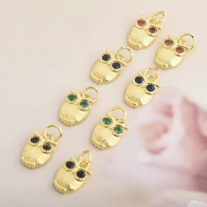 Macro shot of colorful owl pendants with sparkling stones and textured gold plating