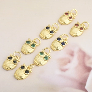 Close-up of eight gold owl charms with colorful cubic zirconia eyes and textured details