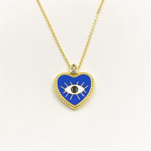 Detail of gold heart pendant with blue enamel evil eye and teardrop zircon accent