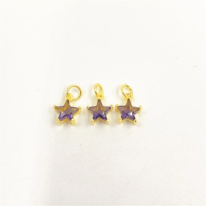 Detailed macro view of three golden star pendants with purple zircon stones on a white surface