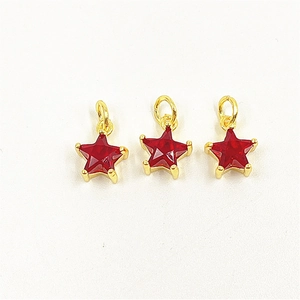 Close-up of three red star-shaped zircon pendants with gold-plated edges and ring loops