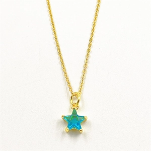 Close-up of blue star-shaped zircon pendant on gold-plated thin cross chain necklace