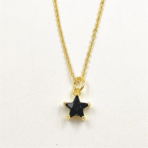 Macro detail of a black star pendant with gold metal frame and sparkling zircon inlay
