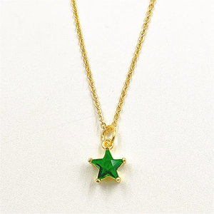 Macro detail of a green star pendant with micro-set zircon and a gold-plated copper chain