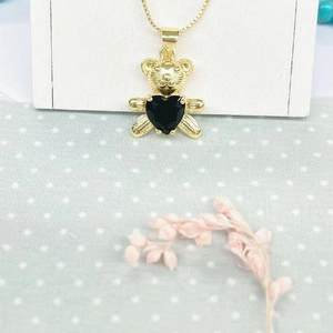 Golden panda pendant necklace with a black heart-shaped stone on a white stand