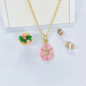 Detail of gold necklace with pink enamel teardrop pendant and square cubic zirconia center