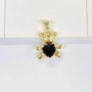 Detail of golden panda pendant with black heart gemstone on a white wood surface