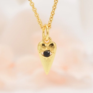 Macro-opname van de vergulde evil eye hart hanger met gehamerde textuur en zirkonia