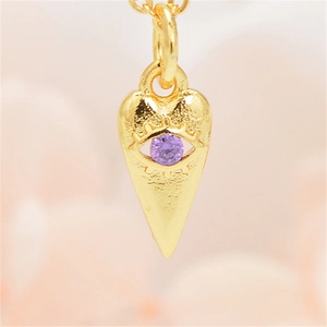 Macro-opname van de gouden hart hanger met boze oog motief en paarse zirkoon