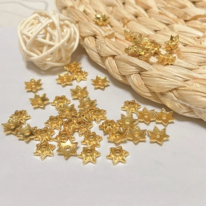 Macro shot of gold star beads for DIY jewelry with center hole on natural textured background